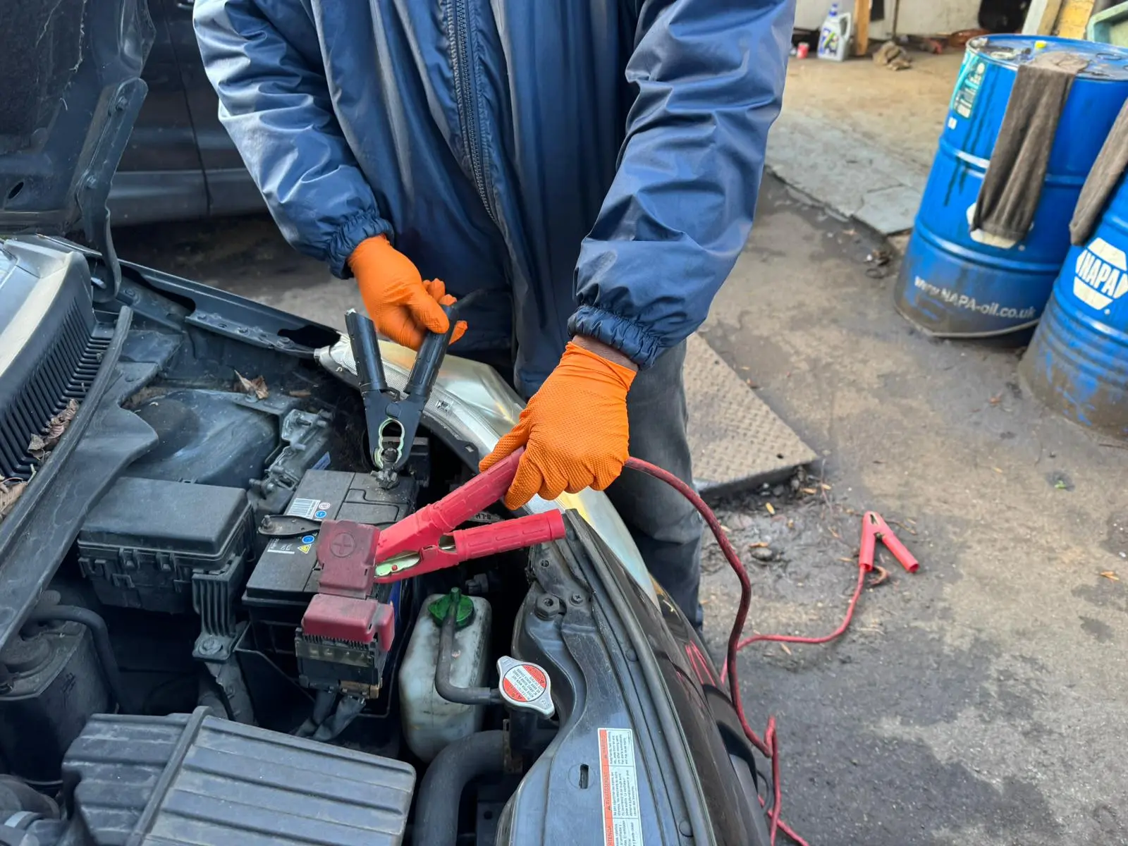 Car battery with jumper cables properly connected showing positive and negative terminals
