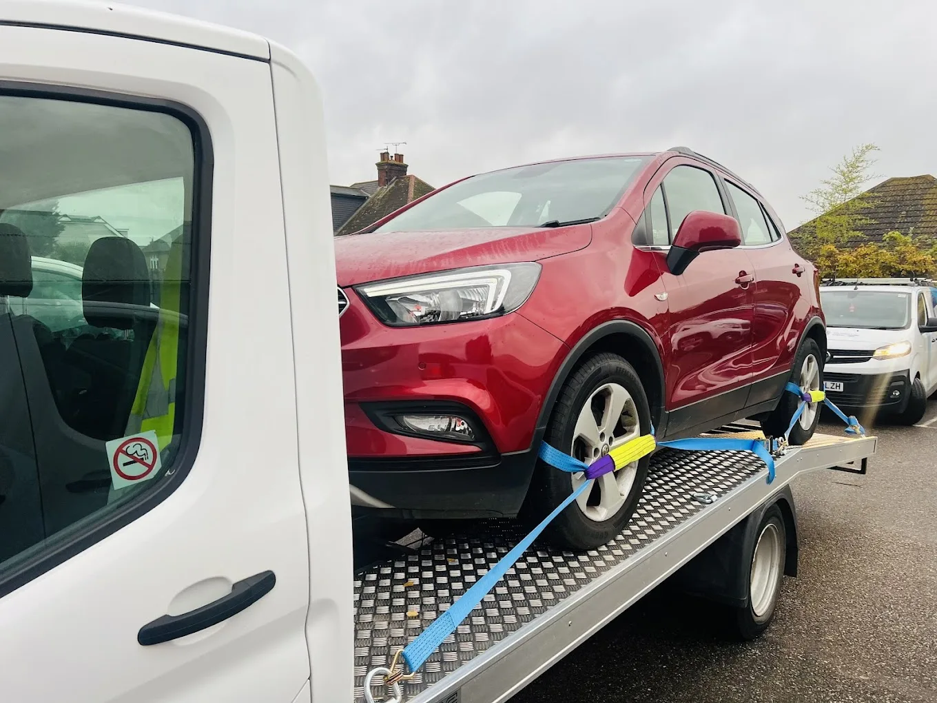 Professional flatbed car recovery truck loading red vehicle onto platform - UK 24/7 breakdown assistance service